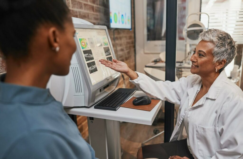 Female eye doctor, explaining eye exam results with looking at the computer screen to her patient