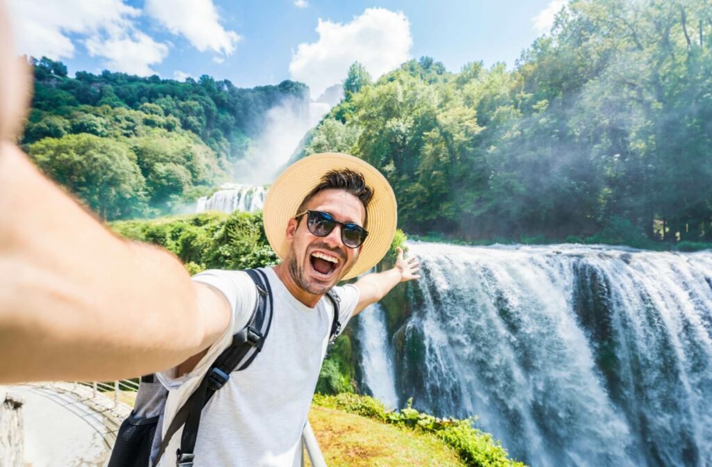 A man enjoys time outdoors in the sun while wearing sunglasses and a wide-brimmed hat to protect his eyes and face.