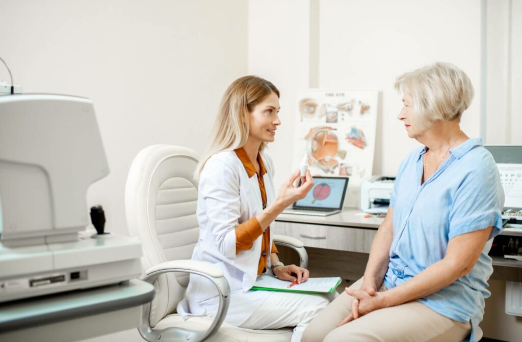 An optometrist holding a bottle of prescription eye drops for dry eyes and explaining to a patient how they can find relief from dry eyes.