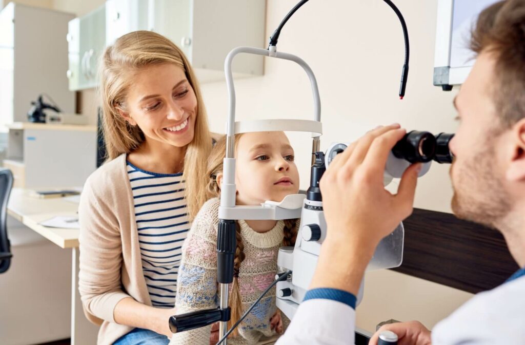 Young girl undergoing an eye exam with a supportive mother nearby ensuring proper visual health at an optometry clinic