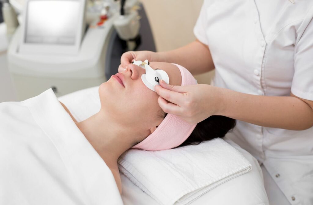 Patient receiving IPL dry eye treatment with protective eye covers in a clinical setting.