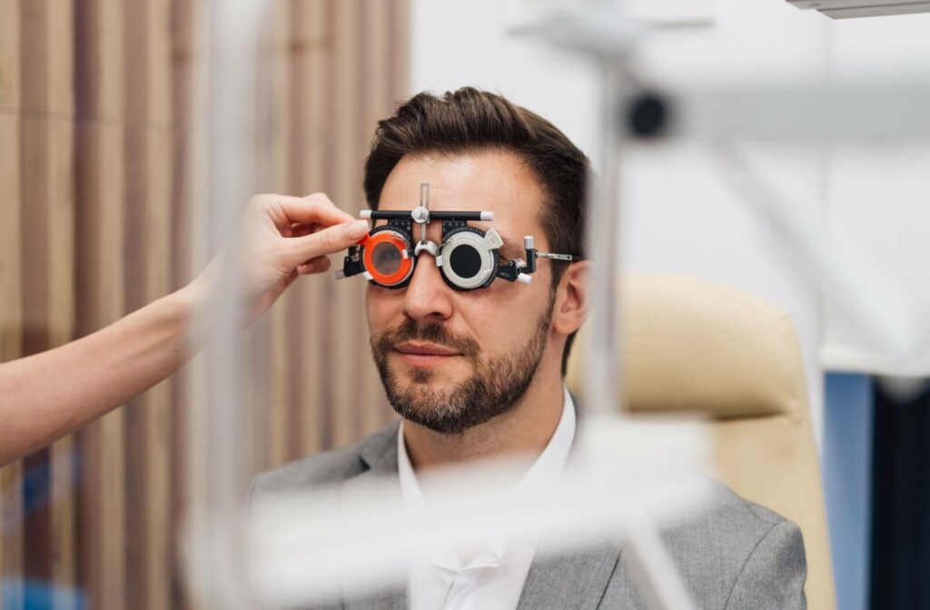 A person wearing a trial frame during an eye exam as an optometrist adjusts the lenses.