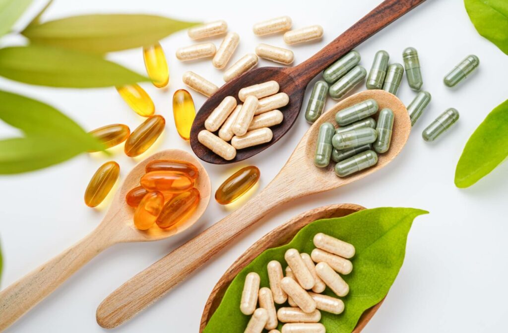 Assorted eye health supplements in wooden spoons with green leaves on a clean white background.
