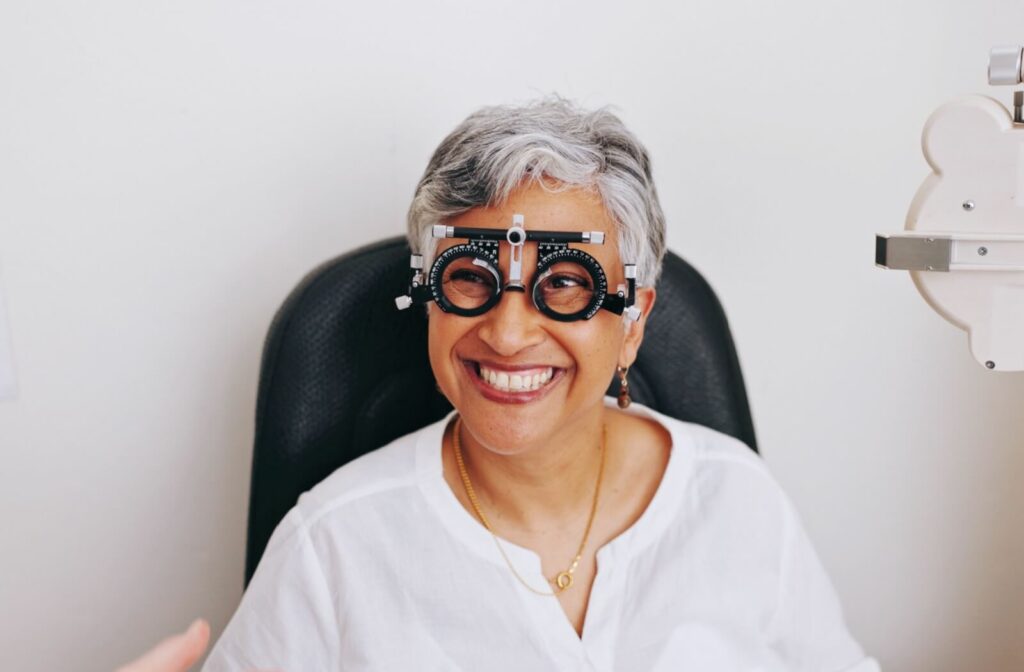 A smiling senior woman wearing a trial frame during a comprehensive eye exam to detect early signs of AMD.